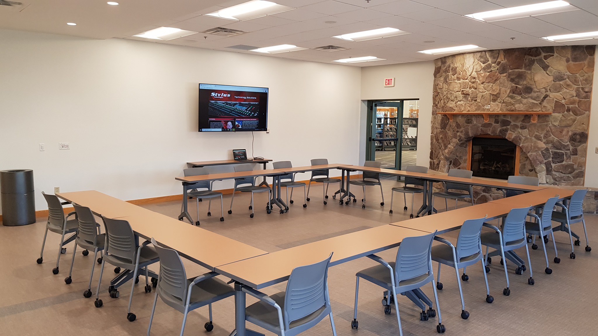Library meeting room with wall-mounted display and fireplace — a Stylus Technologies install