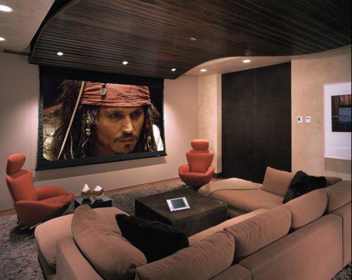 Luxury home theater with large projection screen, tiered seating and ambient lighting